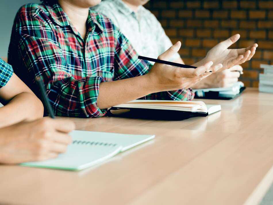 Group of asian students showing hands talking question with teacher in class.