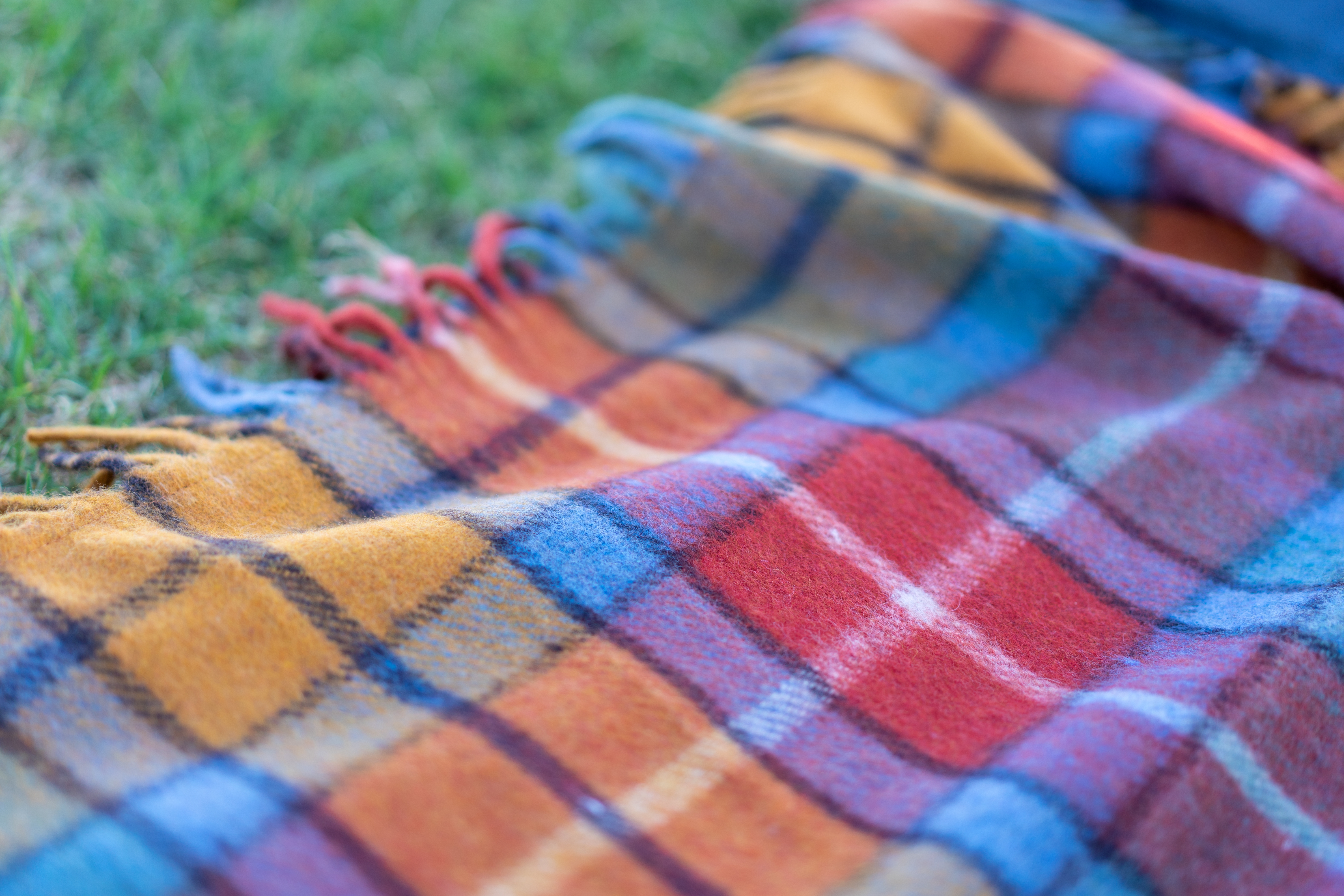 Picnic blanket lies on the grass on a sunny day. Wool checkered picnic blanket